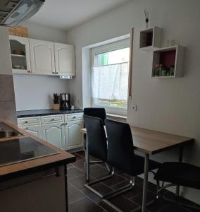 cocina con armarios blancos, mesa y sillas en Ferienwohnung Schloßgast im Oberen Donautal, en Hausen im Tal