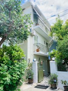 a white building with a green door and some plants at Costas Rooms in Aegina Town