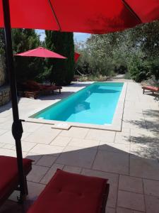 Villa Splendissima Krk - Adults only في كرك: مسبح بمظلة حمراء وكرسي احمر