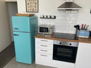 cocina con nevera azul y microondas en Walpole Bay Apartment, en Cliftonville
