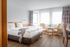 a white bedroom with a bed and a table and chairs at Ringhotel Krone in Friedrichshafen
