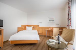 ein Hotelzimmer mit einem Bett, einem Tisch und Stühlen in der Unterkunft Ringhotel Krone in Friedrichshafen