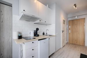 a white kitchen with white cabinets and a wooden door at Narutowicza I by LookAp in Łódź +6 photos