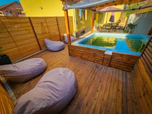 a deck with a swimming pool and pillows next to a house at Vila Alex in Tăşnad