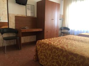 una camera d'albergo con letto, scrivania e sedie di Hotel Eden a Padova