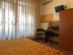 a hotel room with a bed and a desk and a television at Hotel Eden in Padova