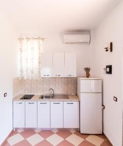a white kitchen with a sink and a refrigerator at Vila Toskaj in Vlorë