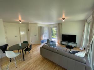 sala de estar con sofá, mesa y TV en Ferienhaus Aalglatt am Deich, 250 m zum Strand en Dierhagen