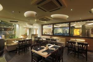 uma sala de jantar com mesas e cadeiras num restaurante em Airport Hotel Le Seasons New Delhi em Nova Deli