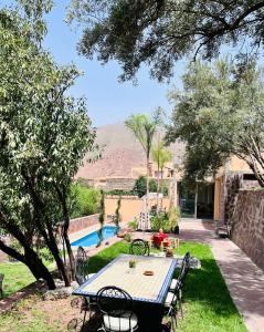 une terrasse avec une table, des chaises et une piscine dans l'établissement Atlas Ijoukak, à Ijjoukak