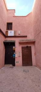 ein rosafarbenes Gebäude mit zwei Garagentüren darauf in der Unterkunft Riad Dar Saad - Hammam & Spa in Marrakesch