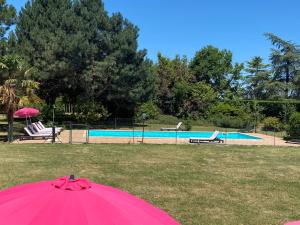 a pink umbrella in front of a swimming pool at Gîte La Maison du Bonheur in Dondas