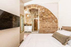 1 dormitorio con 1 cama grande y pared de piedra en Jozefin en ‘Akko