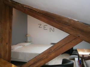 - une chambre avec un lit et un panneau zen sur le mur dans l'établissement Les Charmilles, à Saint-Jean-de-Losne