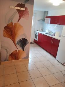 cocina con armarios rojos y suelo de baldosa en Appartement T3 meublé, St Evarzec Bretagne - Le Degemer-Mat, en Saint-Évarzec