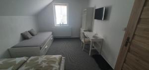 1 dormitorio con cama, escritorio y ventana en Vinný sklep a penzion U Bobule, en Louka