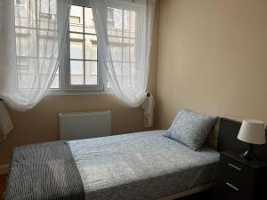 a bedroom with a bed and two windows at Piso en el centro de Laredo a pie de playa in Laredo