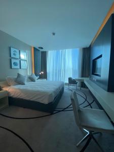 a bedroom with a bed and a tv and a chair at 4Leisure Suites DAMAC Esclusiva Towers in Riyadh