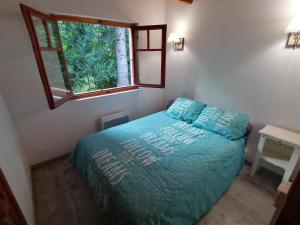 Schlafzimmer mit einem Bett mit blauer Bettwäsche und einem Fenster in der Unterkunft Chalet Le Tyrolien, au coeur du Boréon in Saint-Martin-Vésubie