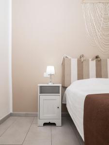 ein Bett mit einem weißen Nachttisch mit einer Lampe in der Unterkunft Luminoso Appartamento sul Lago - Lake Court in Anguillara Sabazia