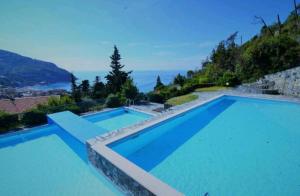a large swimming pool with a view of the ocean at Elegant and Sea View Excelsior Apartment in Levanto