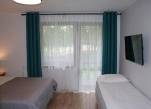 a bedroom with two beds and a window with green curtains at Villa Amiro in Władysławowo