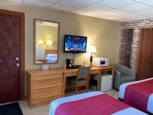 a hotel room with a desk and a tv on the wall at La Paysanne Motel & Hotel in Sherbrooke