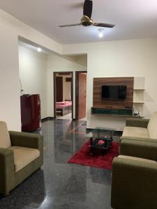 a living room with two couches and a flat screen tv at Haven Homes in Yelahanka