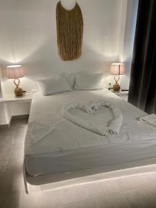 a white bed with a heart shaped pillow on it at Iakovos' Luxury House in Tinos Town
