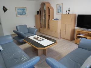 sala de estar con sillas azules, mesa y TV en Ferienhaus am Flaumbach, en Blankenrath