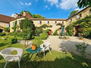 a garden with chairs and a table and a building at Ferme de Tayac - Charme avec Pool in Les Eyzies-de-Tayac