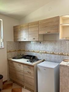 a kitchen with wooden cabinets and a white refrigerator at Apartments Villa Sveti Nikola in Budva