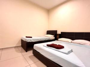 a bedroom with two beds with white sheets and red towels at VGO House in Malacca