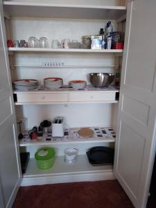 un garde-manger ouvert avec de la vaisselle et des bols sur les étagères dans l'établissement gîte chez Anne et Flo, à Villefranche-Saint-Phal