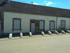 a building with a row of stone barriers in front of it at gîte chez Anne et Flo in Villefranche-Saint-Phal