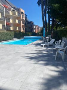 einen Pool mit zwei weißen Stühlen und einem Pool in der Unterkunft Appartement La Baule;Pornichet in La Baule
