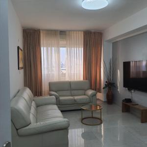 a living room with a couch and a television at Lovely three-room apartment above the promenade in Ashdod