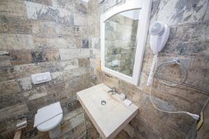 a bathroom with a sink and a toilet and a mirror at Hotel Sarajet e Pashait 1 in Dhërmi