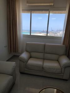 a living room with a couch and a large window at Lovely three-room apartment above the promenade in Ashdod