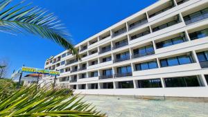 ein Apartmenthaus mit einer Palme davor in der Unterkunft Hotel Aqua Park in Eforie Nord