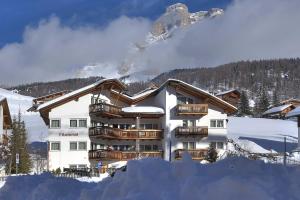 a hotel with a snow covered mountain in the background at Ciasa Milandura in San Cassiano