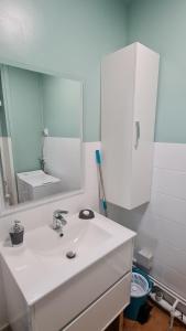ein Badezimmer mit einem weißen Waschbecken und einem Spiegel in der Unterkunft Mazamet : Résidence du Musée centre ville. in Mazamet
