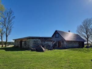 a stone house on a green field with some rocks at Soonlepa häärber in Soonlepa