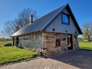 a stone building with a metal roof on a field at Soonlepa häärber in Soonlepa