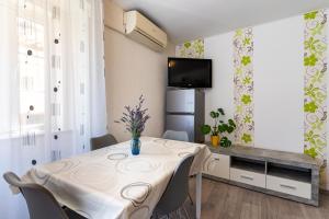 a dining room with a table with chairs and a tv at Apartman Antonija in Cres