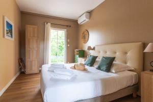 een slaapkamer met een groot wit bed en handdoeken bij Hôtel & SPA Ventoux Provence "Domaine des Tilleuls" in Malaucène