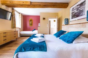 a large bedroom with two beds with blue pillows at Hôtel & SPA Ventoux Provence "Domaine des Tilleuls" in Malaucène