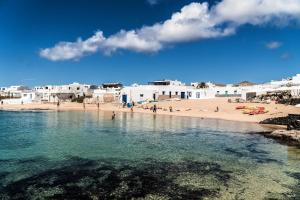 a beach with white buildings and people in the water at Apartamento vacacional en Orzola Lanzarote in Orzola