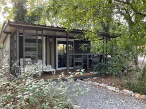 una pequeña casa negra con un banco en el patio en Les Chalets de Labeaume, en Labeaume