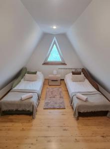 Cette chambre mansardée comprend 3 lits et une fenêtre. dans l'établissement Apartment na poddaszu, à Augustów